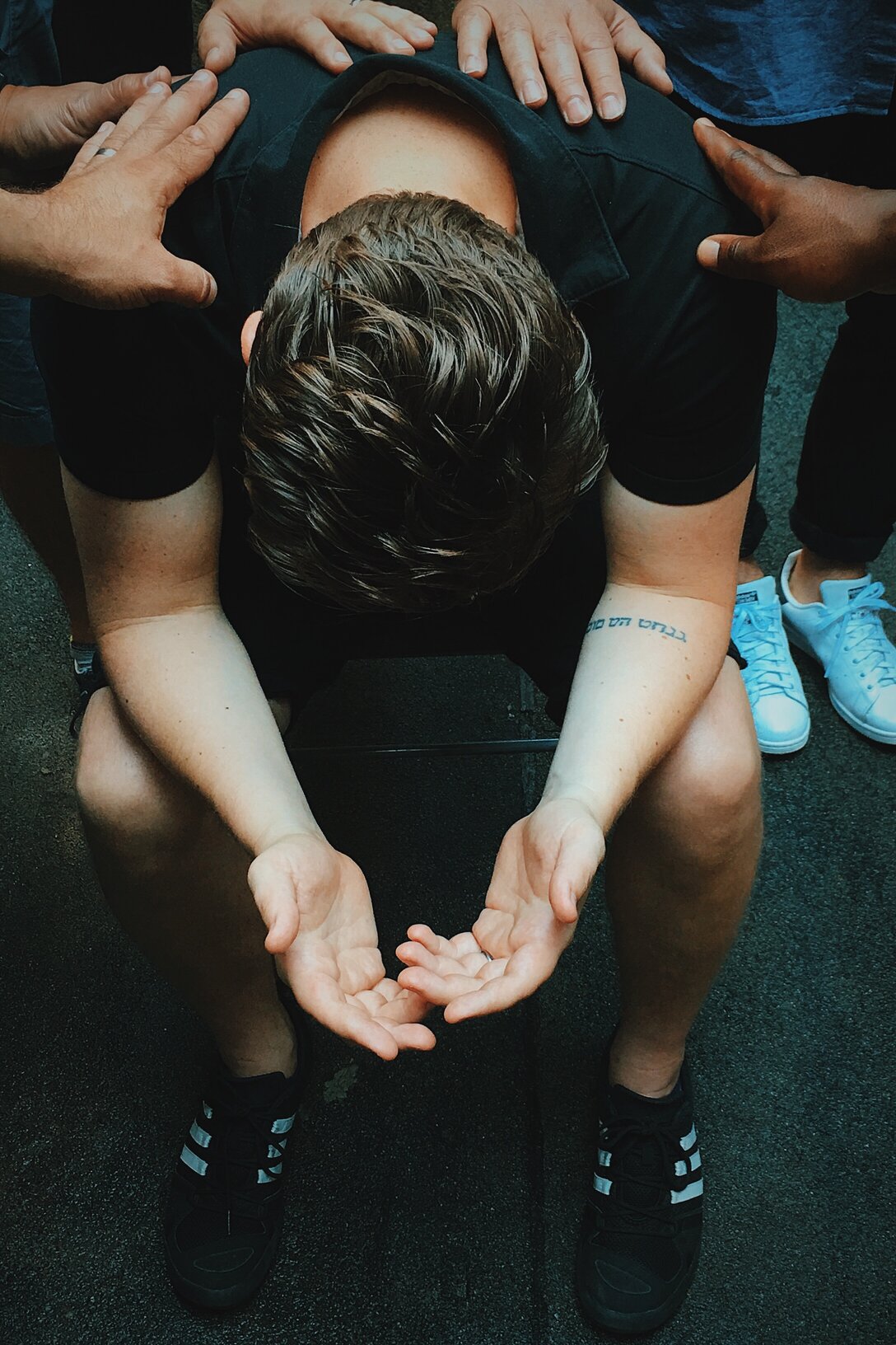 An image of a person praying while other people lay their hands on him.